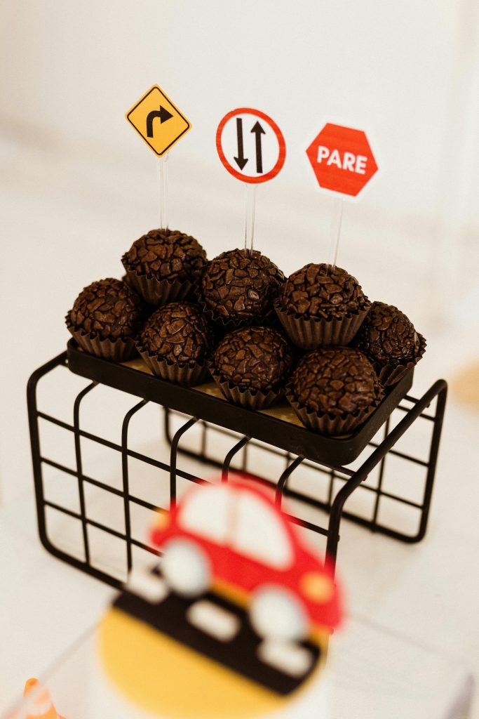 Chocolats brigadeiros présentés avec des décorations ludiques de panneaux de signalisation pour une fête à thème.