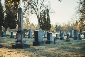Un paysage de cimetière paisible avec des pierres tombales et des arbres dénudés par temps clair.