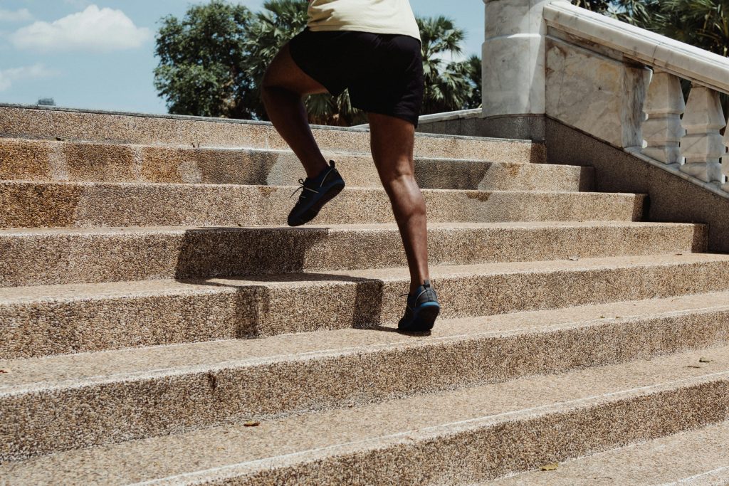 Une personne courant dans des escaliers en béton en extérieur, illustrant la forme physique et l'exercice en milieu urbain.