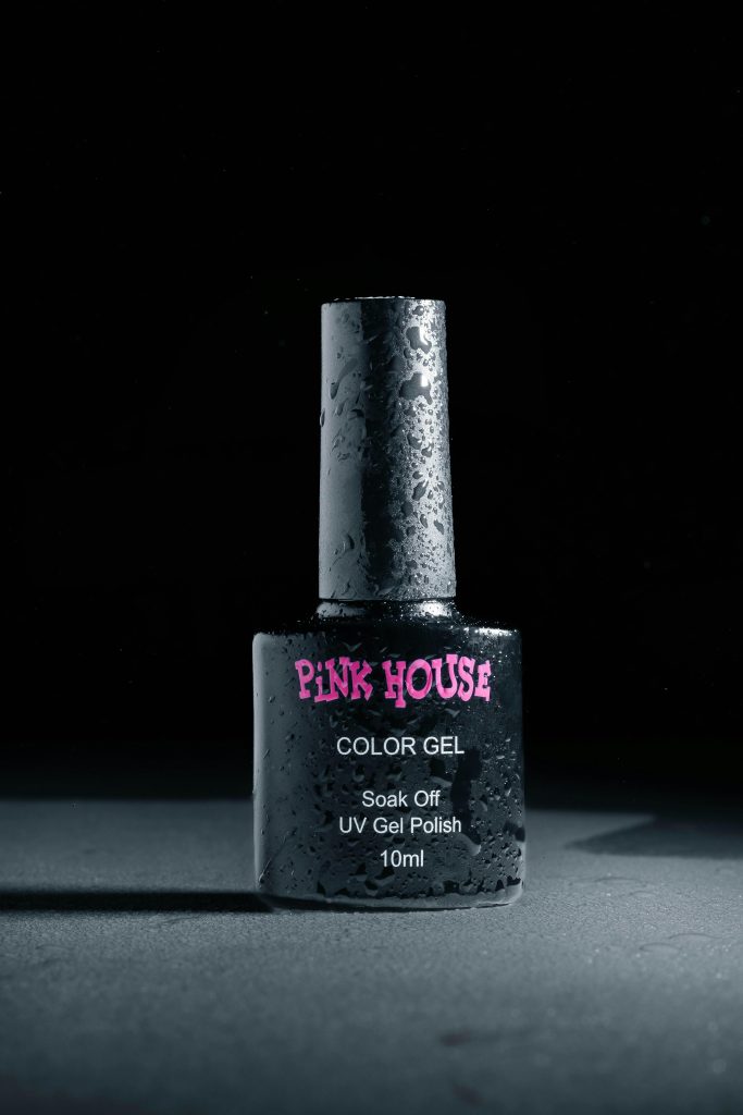 Gros plan sur un flacon de vernis à ongles en gel UV avec des gouttelettes d'eau, éclairage studio.