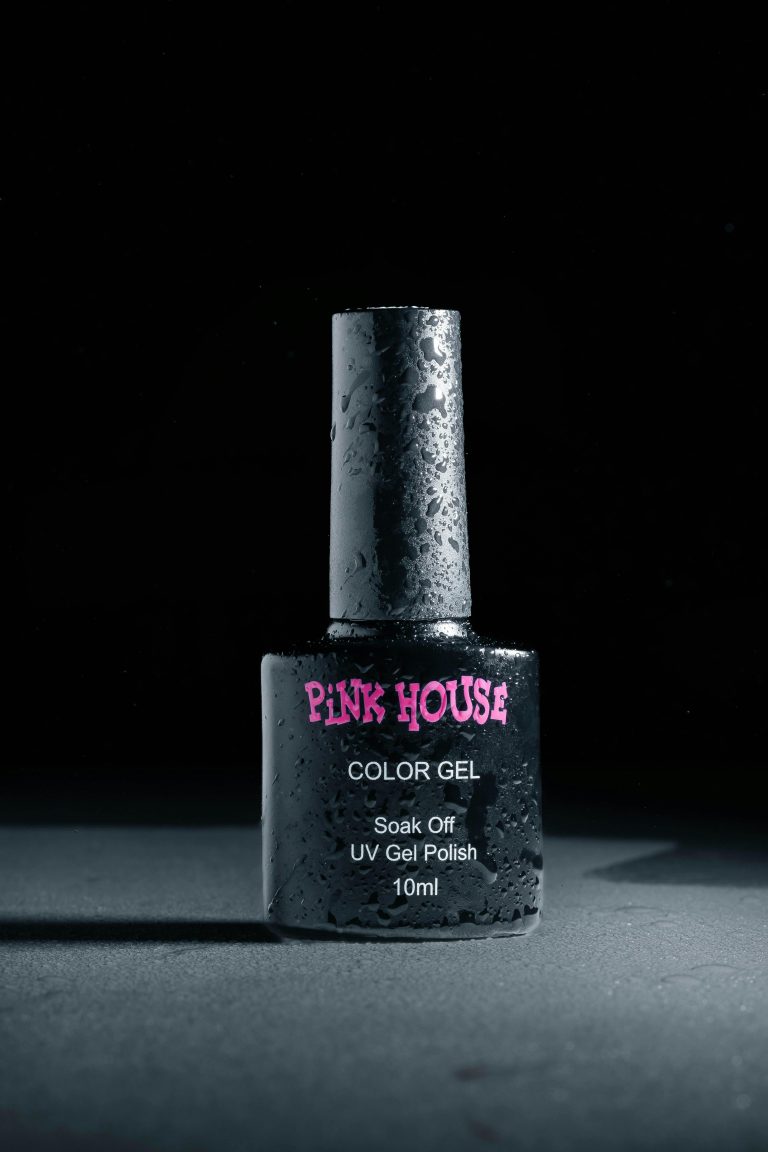 Gros plan sur un flacon de vernis à ongles en gel UV avec des gouttelettes d'eau, éclairage studio.