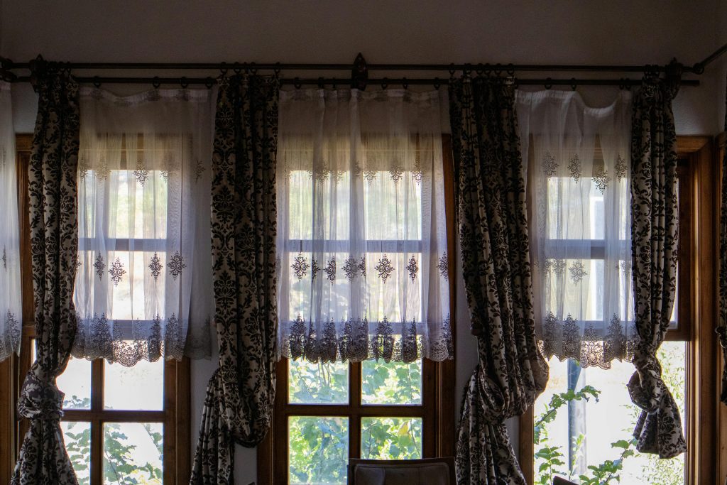 Sunlit room with elegant traditional curtains overlooking a garden view. Pièce ensoleillée avec des rideaux traditionnels élégants donnant sur une vue sur le jardin.