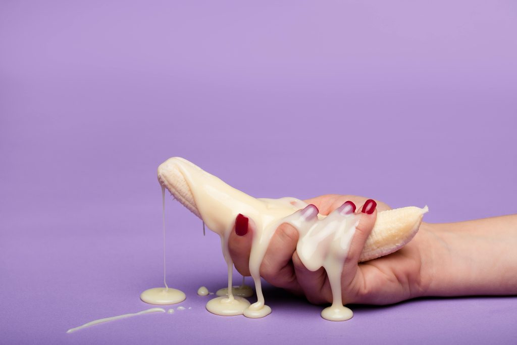 Creative conceptual image of a banana with cream on a purple backdrop, symbolizing indulgence. Image conceptuelle créative d'une banane avec de la crème sur un fond violet, symbolisant l'indulgence.