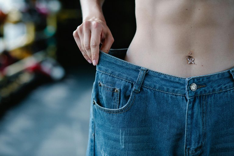 Close-up view of a slim waist and loose jeans representing weight loss or fitness progress. Gros plan sur une taille fine et un jean ample représentant une perte de poids ou une progression en fitness.
