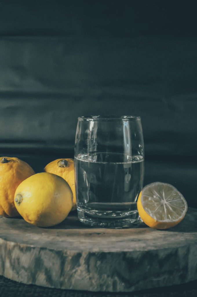 Glass of refreshing water with lemons on a wooden board, perfect for a fresh summer vibe. Un verre d'eau rafraîchissante avec des citrons sur une planche en bois, parfait pour une ambiance estivale fraîche.
