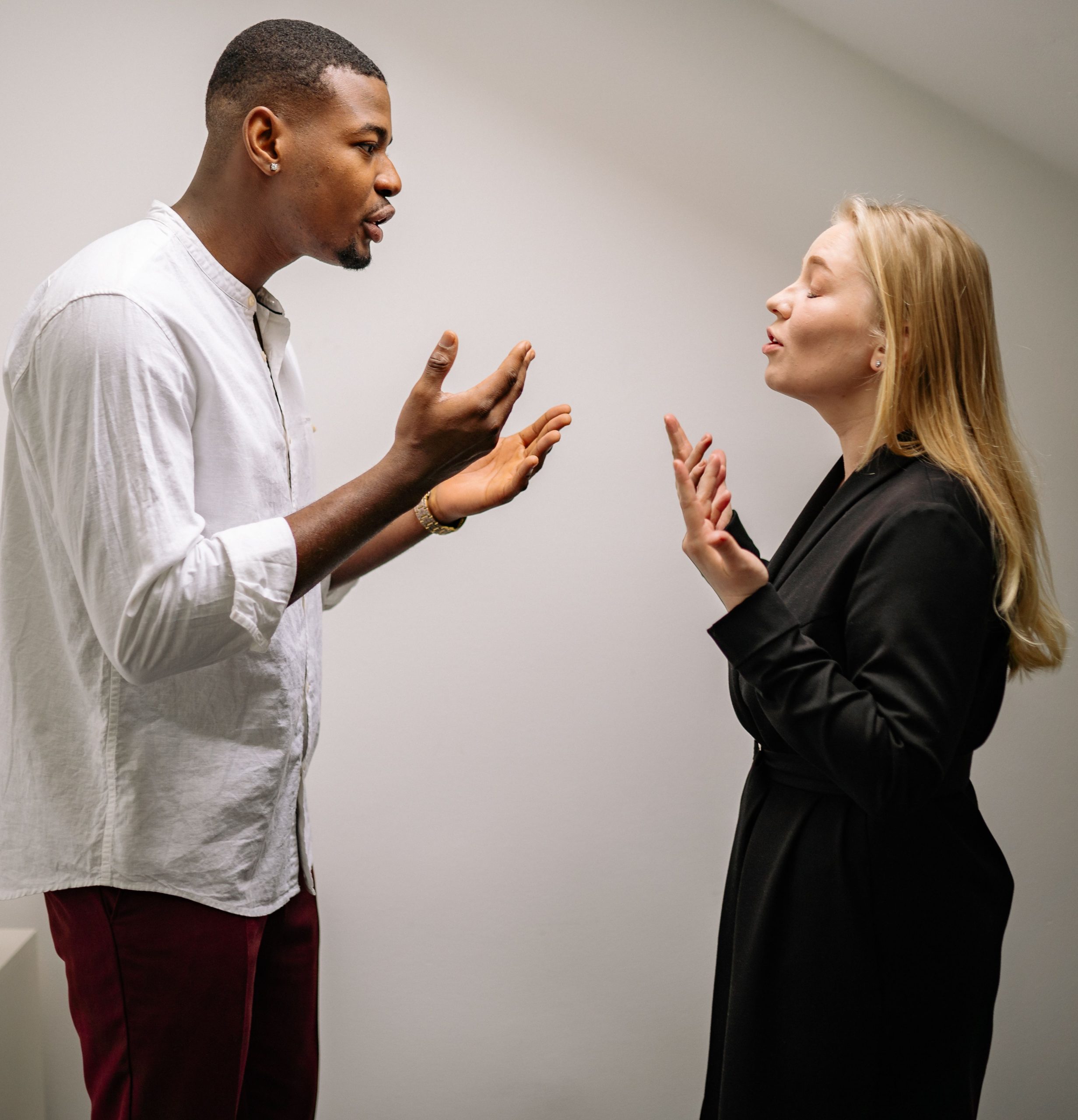 A couple engaged in a heated argument indoors, expressing strong emotions and gestures. Un couple engagé dans une dispute animée à l'intérieur, exprimant des émotions fortes et des gestes.