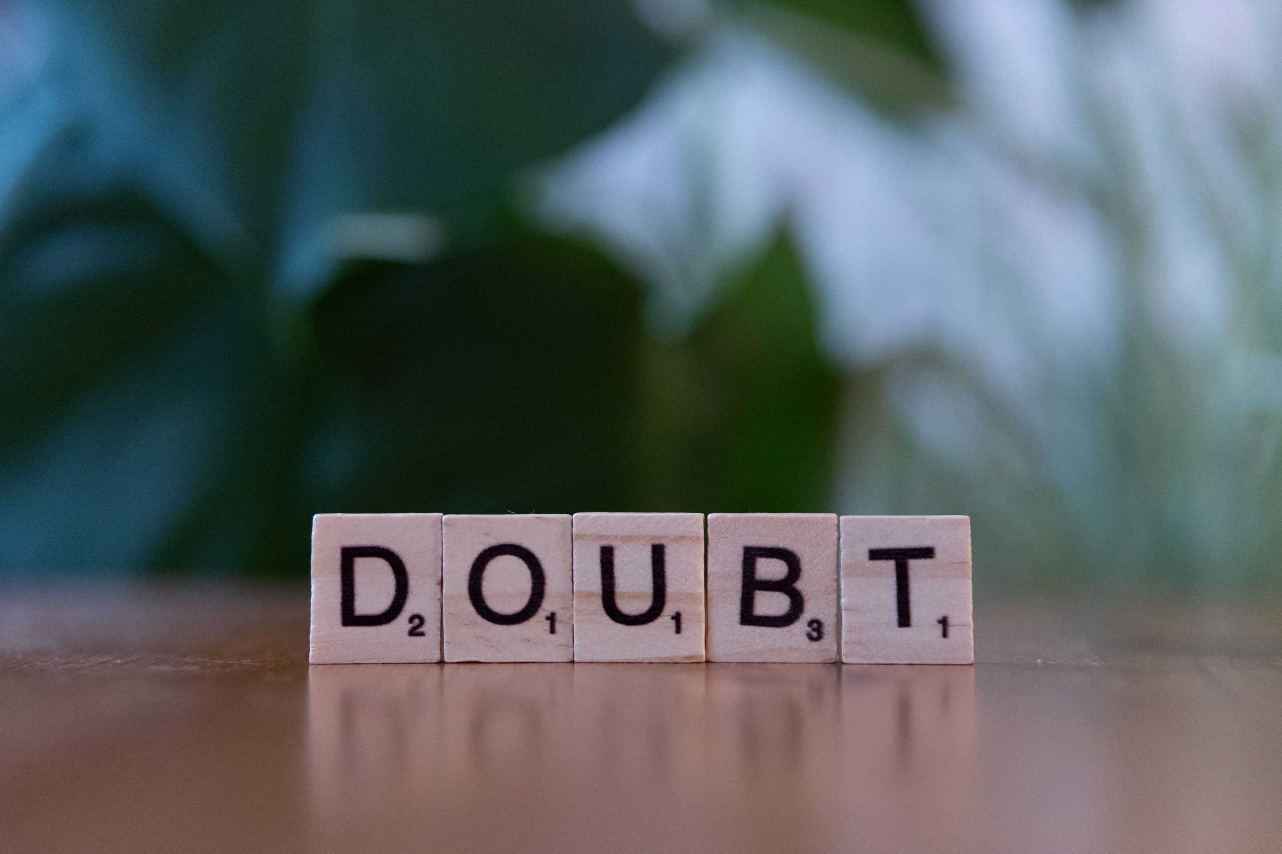 Close-up of Scrabble tiles spelling 'doubt' on a wooden surface, conveying uncertainty. Gros plan sur des tuiles de Scrabble orthographiant « doute » sur une surface en bois, évoquant l'incertitude.