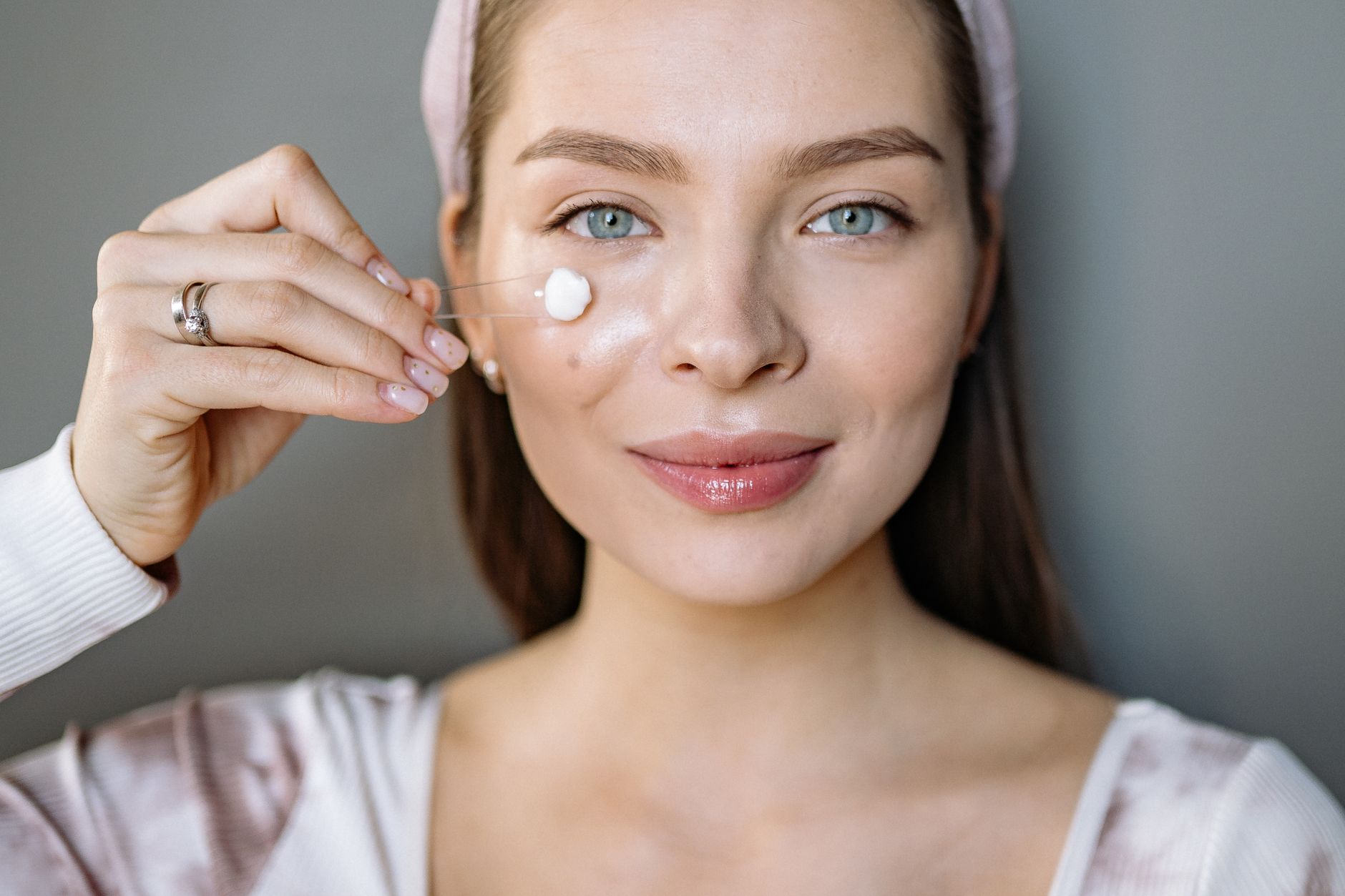 Jeune femme applique sa crème hydratante en souriant